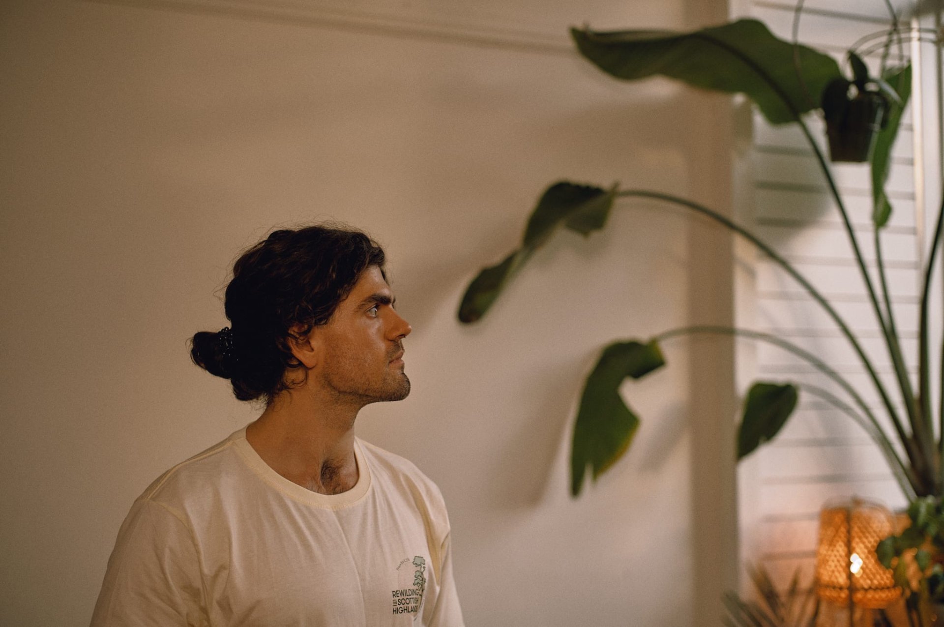 Joe sitting quietly in profile beside a plant